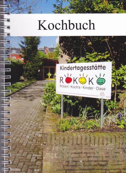 Foto des Spiral-Kochbuchs mit dem Eingang einer Kita und einem Schild "Kindertagesstätte ROKOKO Robert-Kochs-Kinder-Oase".