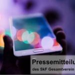 Foto von einer Hand, die ein Smartphone hält; bunte Lichter im Hintergrund. Oben links das SkF-Logo, unten rechts Text: Pressemitteilung des SkF Gesamtverein e. V.