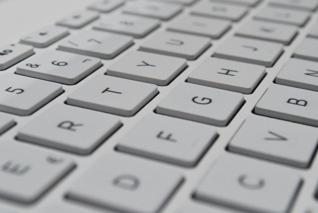 Foto von einer weißen Computertastatur in Nahaufnahme, mit scharfen Buchstaben- und Zahlentasten in diagonaler Anordnung.